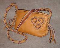  This small two-tone bag is about 9" long by 6" high. It has a zipper across the top of it. The long 8 strand braided shoulder strap has tassels hanging from the ends of it. There is (what I call) a 'tri-loop' applique braided to the side of it. 